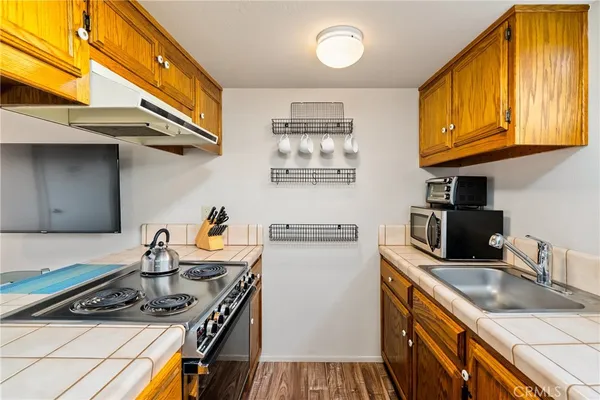 a kitchen with stainless steel appliances a stove a sink dishwasher and cabinets with wooden floor