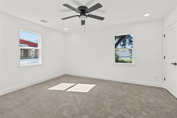 an empty room with windows and fan