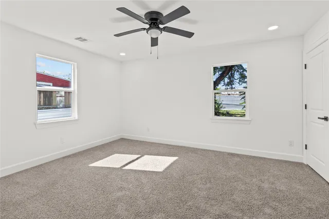 an empty room with windows and fan