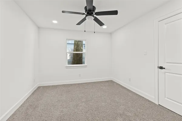an empty room with a window and a fan