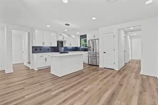 a large kitchen with stainless steel appliances a refrigerator and a stove top oven