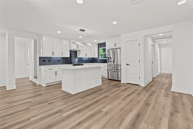 a large kitchen with stainless steel appliances a refrigerator and a stove top oven