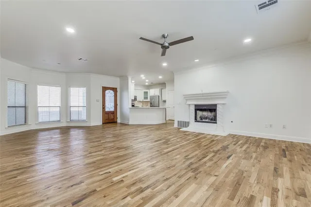 an empty room with wooden floor and a kitchen