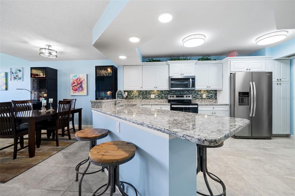 5151 Isla Key Boulevard South, Unit 421 St. Petersburg, FL 33715 - Photo 7 of 61 a kitchen with stainless steel appliances granite countertop a stove refrigerator and chairs