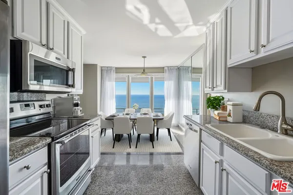 a view of a kitchen with kitchen island a sink a counter space and stainless steel appliances