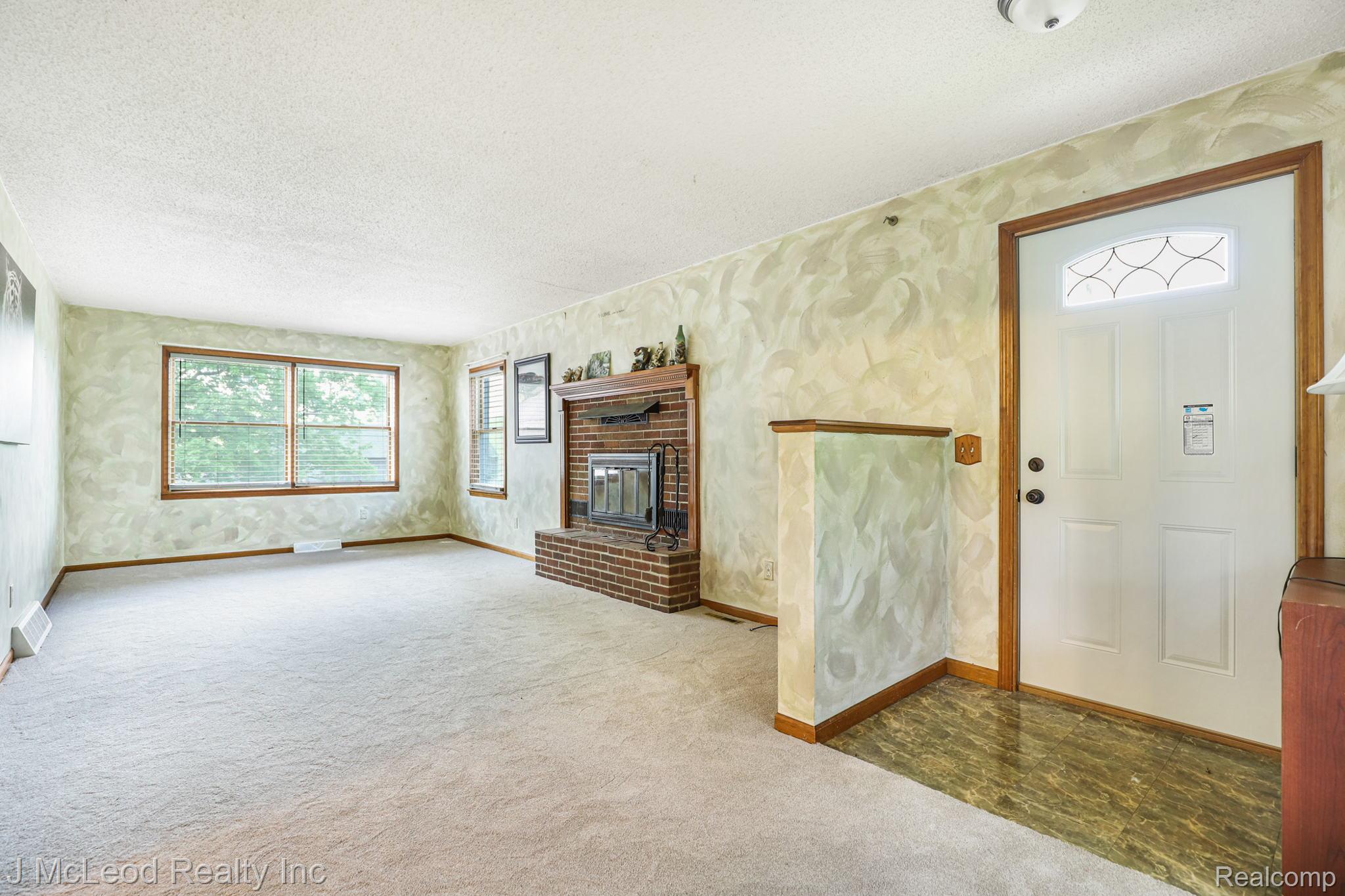 Brick-clad fireplace, wood-framed windows, and a front entry door with an arched decorative glass insert