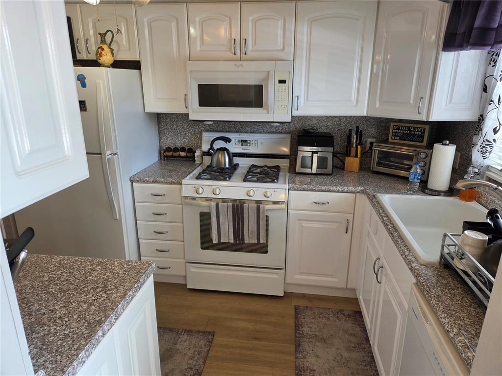 7 Dunoon Place, Unit 309 Dunedin, FL 34698 - Photo 5 of 25 a kitchen with stainless steel appliances granite countertop a stove a sink and a refrigerator