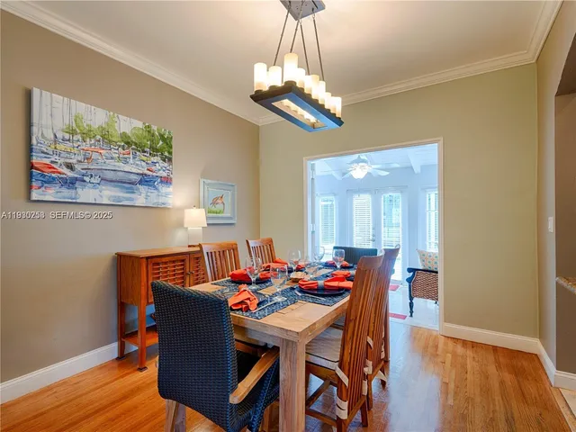 a dining room with wooden floor a chandelier a wooden table and chairs
