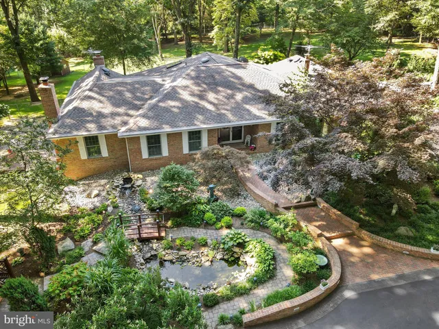 a view of a white house with a yard plants and large tree