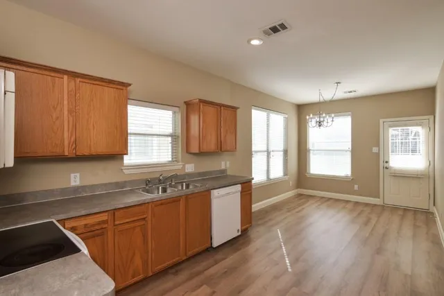a kitchen with stainless steel appliances granite countertop cabinets wooden floor and a window
