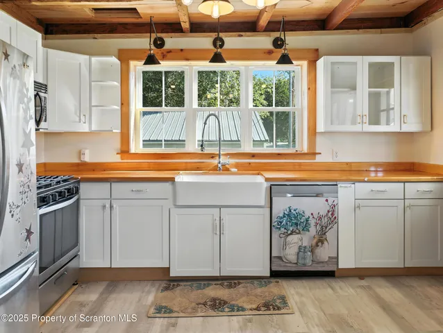 a view of a kitchen with a sink and dishwasher with wooden floor