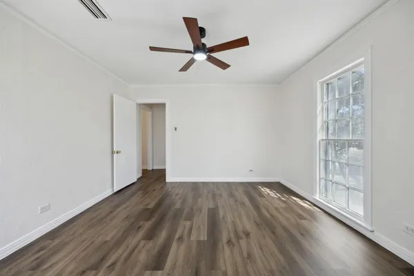 an empty room with wooden floor a ceiling fan and windows