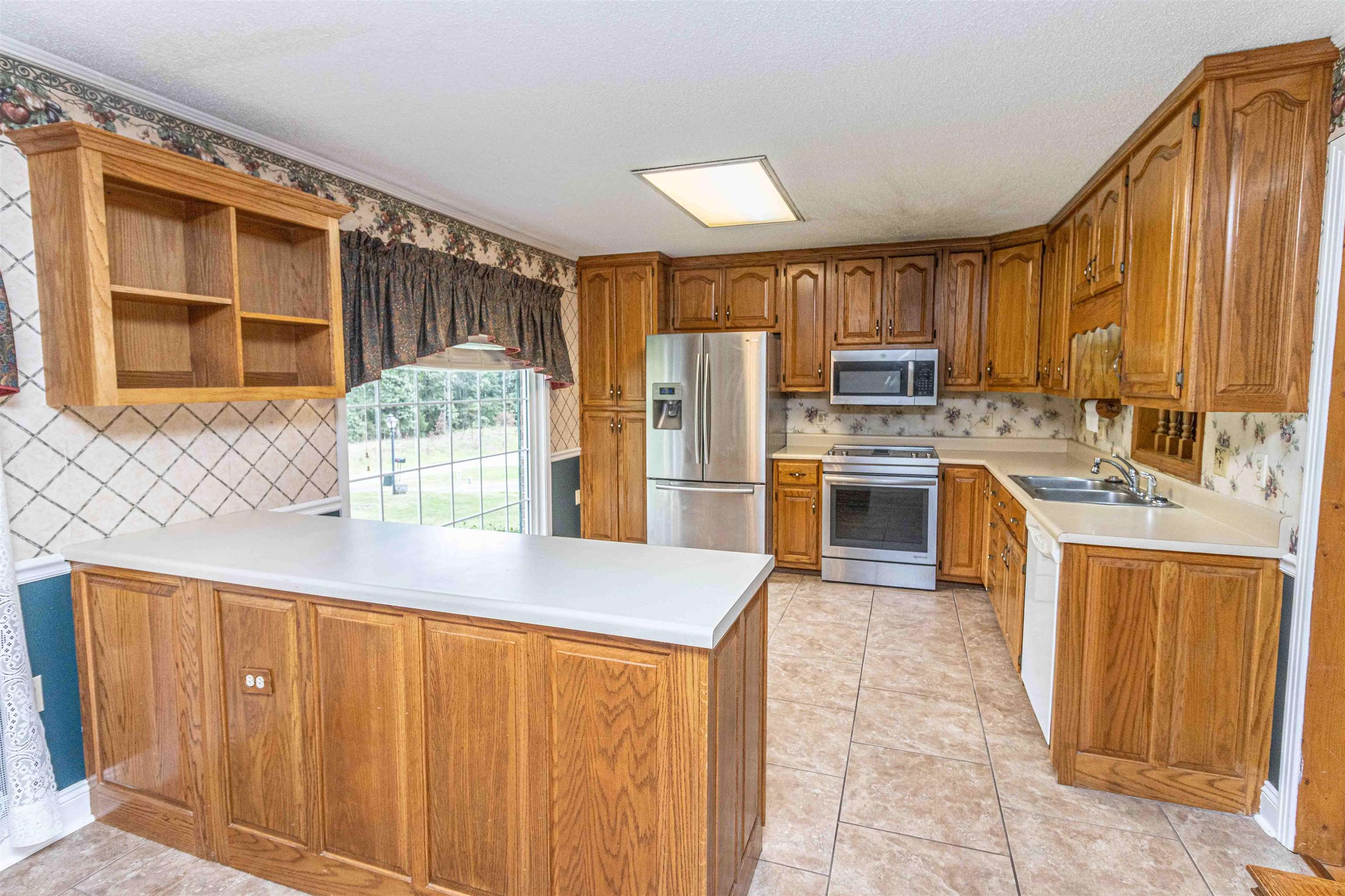 239 Old Road South, Unit 5 Selmer, TN 38375 - Photo 8 of 34 a kitchen with stainless steel appliances granite countertop a refrigerator and wooden cabinets