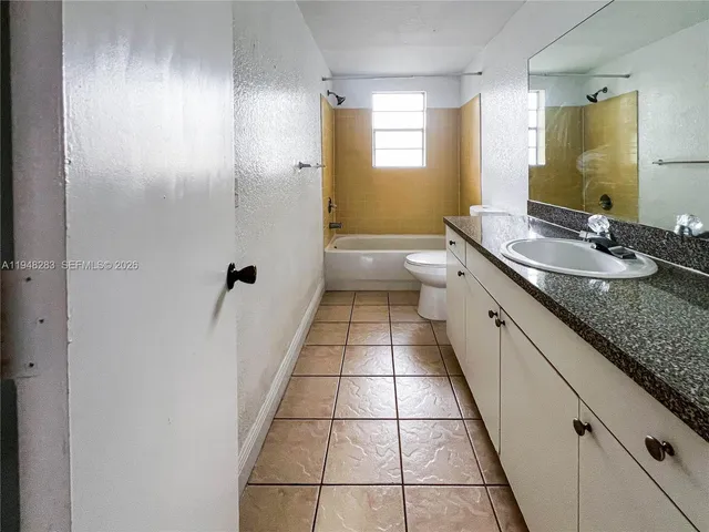 a bathroom with a granite countertop toilet sink and mirror