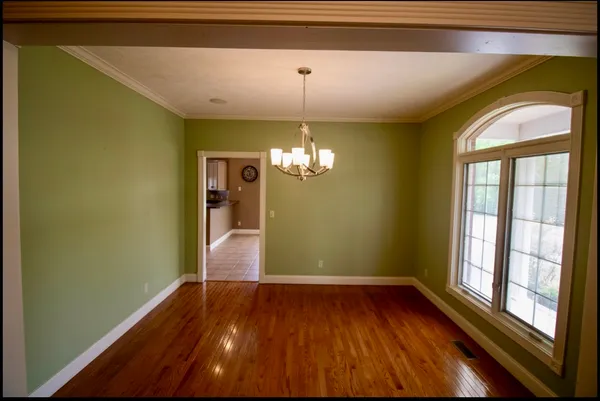 a view of a room with wooden floor chandelier and a window