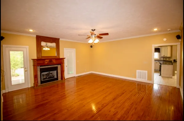 a view of a livingroom with a fireplace wooden floor and a kitchen