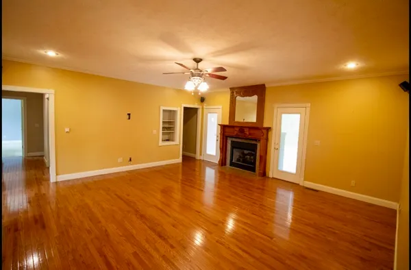 a view of a livingroom with a fireplace a ceiling fan and wooden floor