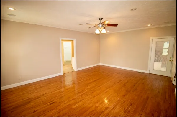 an empty room with wooden floor and fan