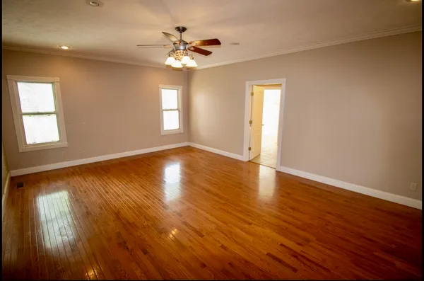 an empty room with wooden floor and windows