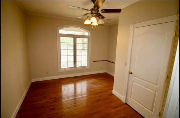 a view of an empty room with wooden floor and a window