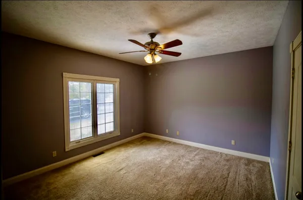 an empty room with windows and fan