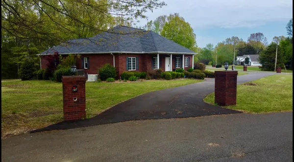 a front view of a house with a garden and trees