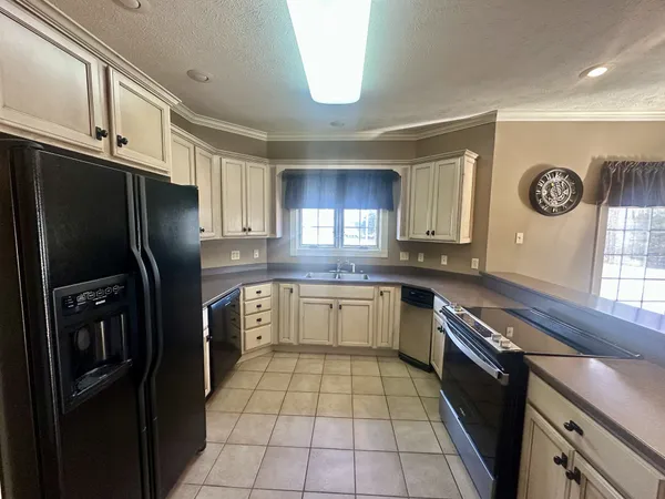 a kitchen with a refrigerator a stove top oven a clock and a window