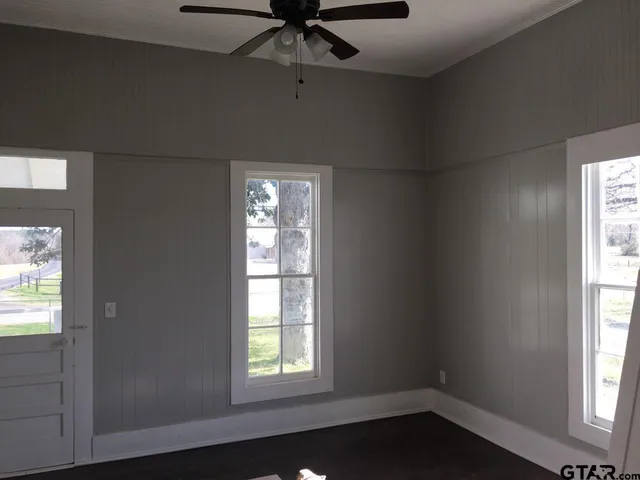 an empty room with windows and fan