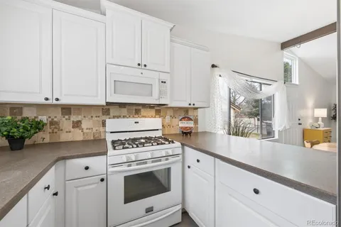 a kitchen with granite countertop white cabinets and white appliances