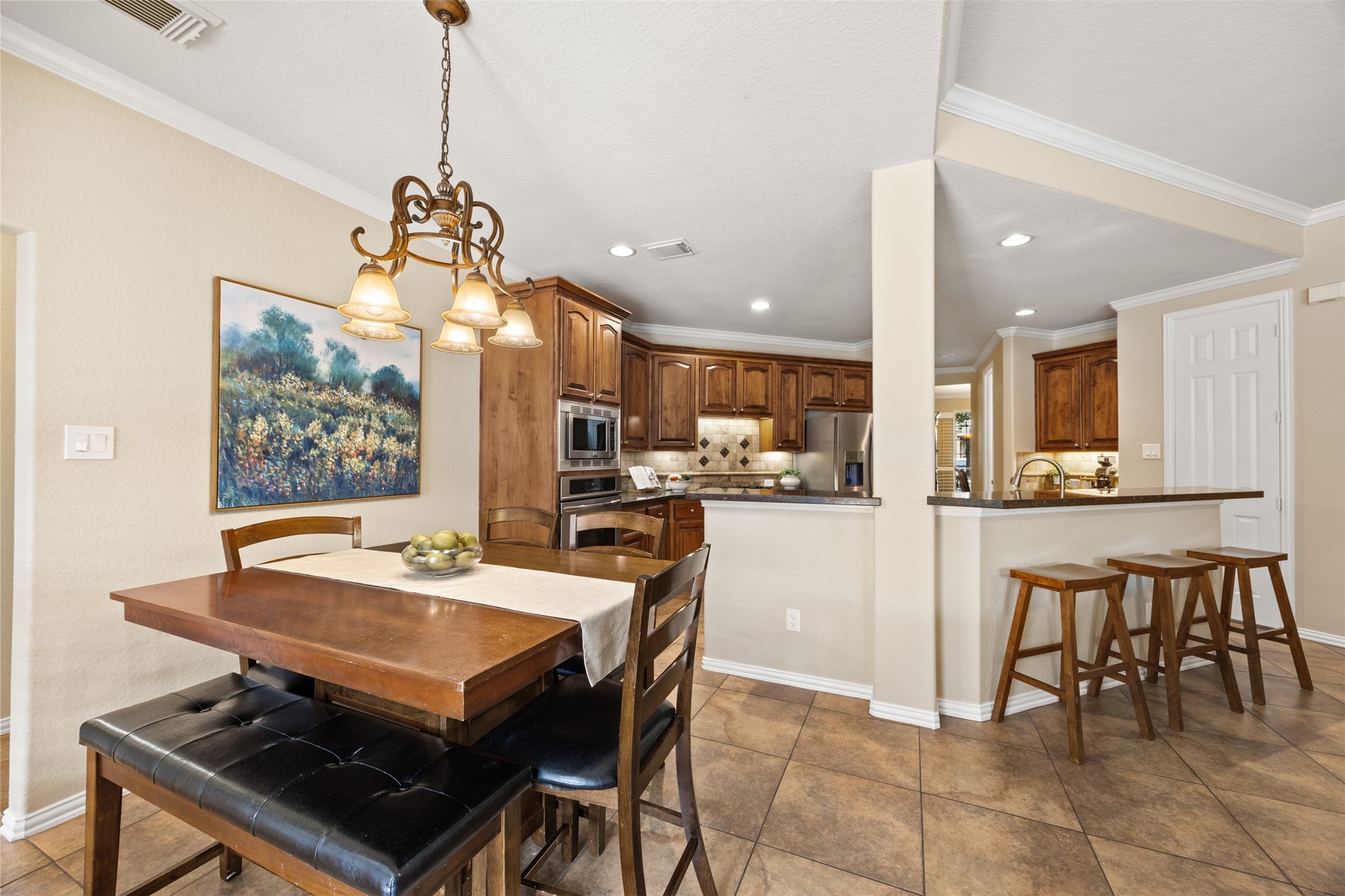 2603 Hendricks Lakes Drive Spring, TX 77388 - Photo 15 of 50 Charming breakfast area with pool views, elegant chandelier, open sightlines to the kitchen, and bar seating—perfect for casual meals and everyday gatherings.