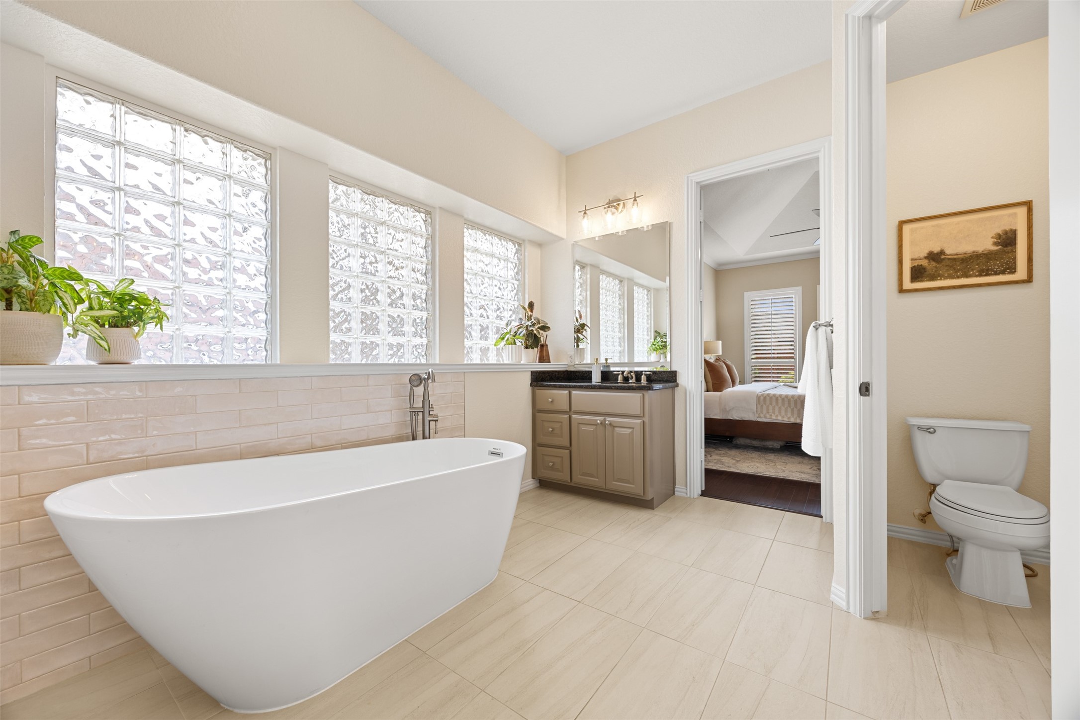 2603 Hendricks Lakes Drive Spring, TX 77388 - Photo 24 of 50 Primary bath retreat featuring a freestanding soaking tub set beneath elegant glass block windows, granite vanity, and private water closet. Seamless access to the bedroom creates a true spa-like suite experience.