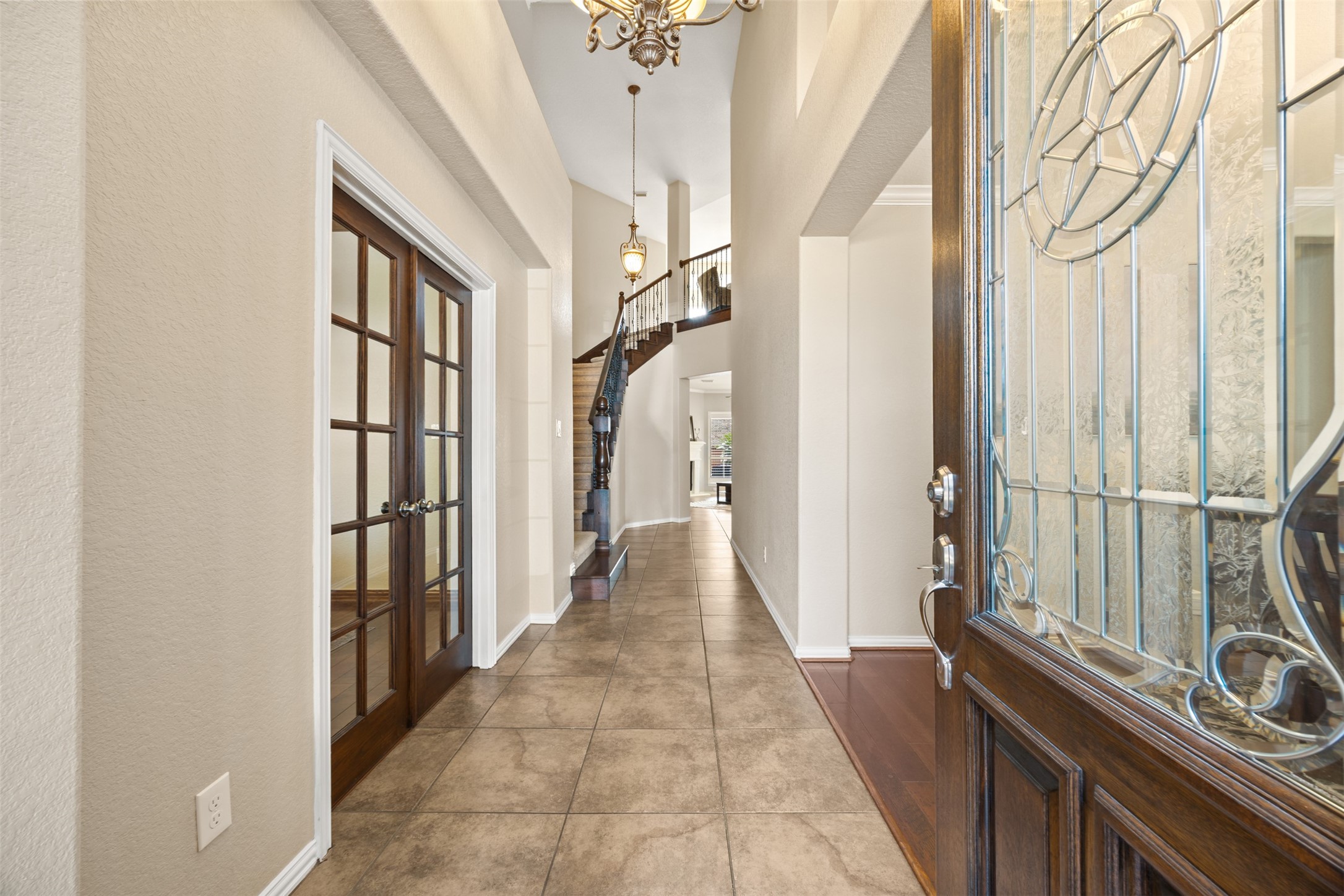 2603 Hendricks Lakes Drive Spring, TX 77388 - Photo 5 of 50 Grand two-story entry with soaring ceilings, elegant chandelier, tile flooring, and a sweeping staircase that creates an impressive first impression. French doors off the foyer offer a private office or flex space, adding functionality and additional storage options.