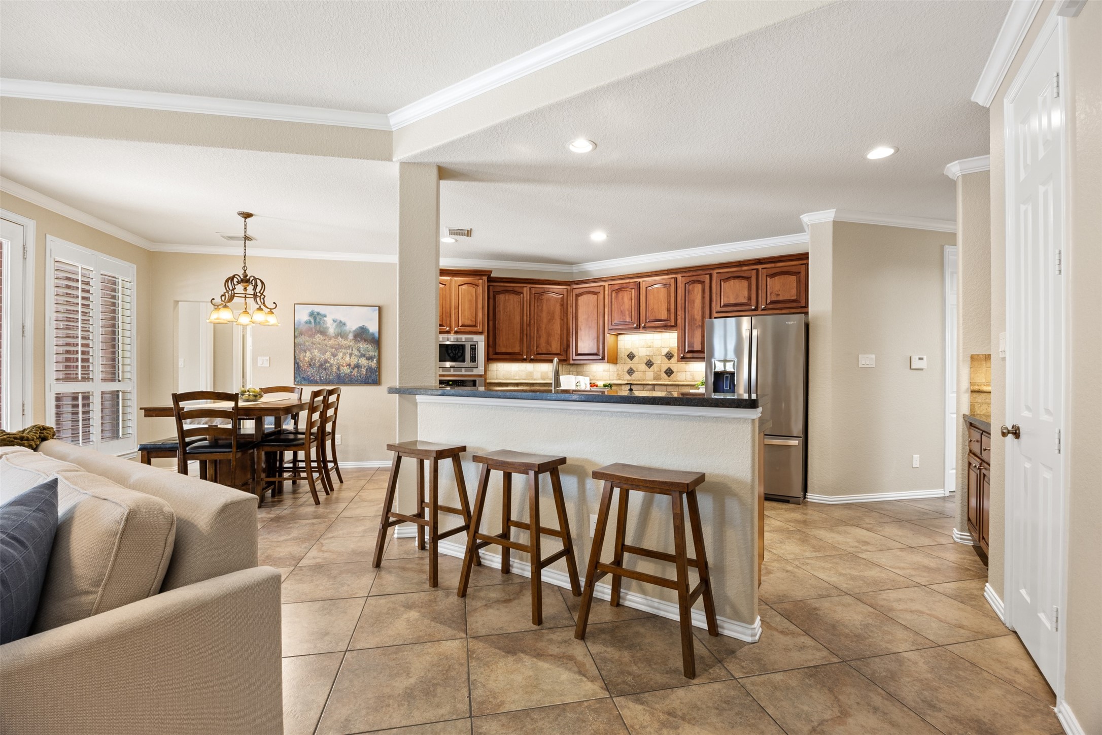 2603 Hendricks Lakes Drive Spring, TX 77388 - Photo 8 of 50 Open-concept kitchen featuring rich wood cabinetry, granite countertops, breakfast bar seating, stainless steel appliances, and seamless flow into the breakfast and living areas—ideal for everyday living and entertaining.