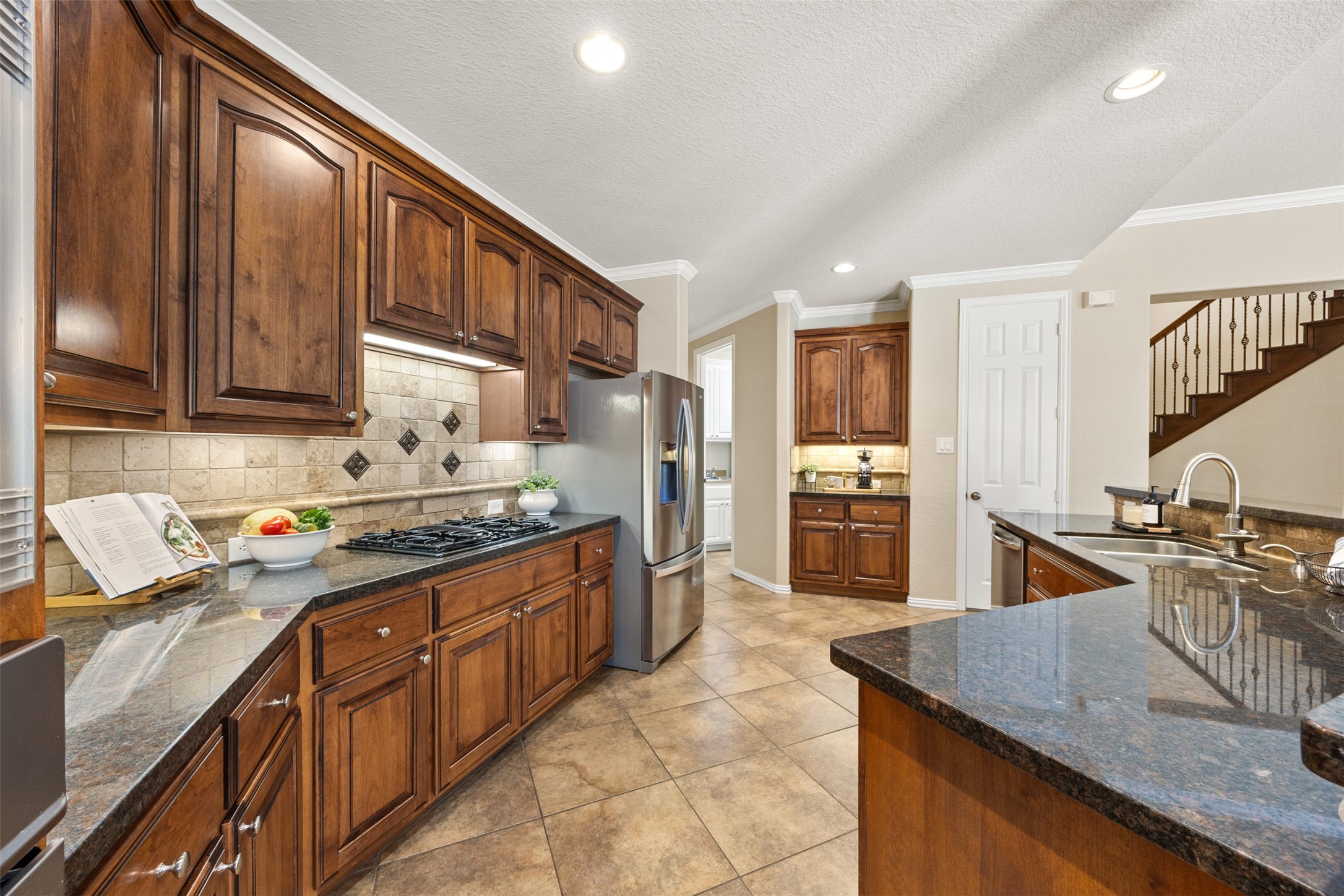 2603 Hendricks Lakes Drive Spring, TX 77388 - Photo 10 of 50 Spacious chef’s kitchen with abundant custom cabinetry, granite surfaces, decorative tile backsplash, stainless appliances, and a generous breakfast bar—designed for both function and style.