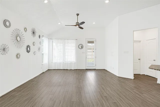 an empty room with wooden floor and windows