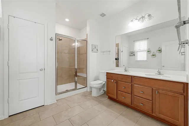 a spacious bathroom with a double vanity sink toilet mirror and shower