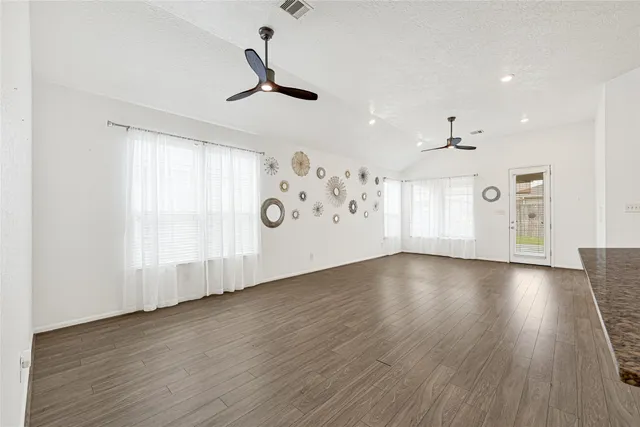 a view of an empty room with window and wooden floor
