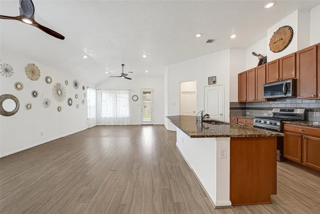 a kitchen with stainless steel appliances granite countertop a stove and a wooden floors
