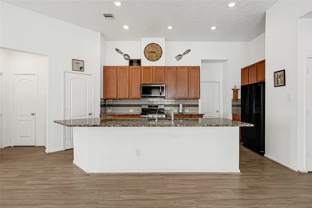 a large kitchen with stainless steel appliances granite countertop a stove a refrigerator a sink and a microwave