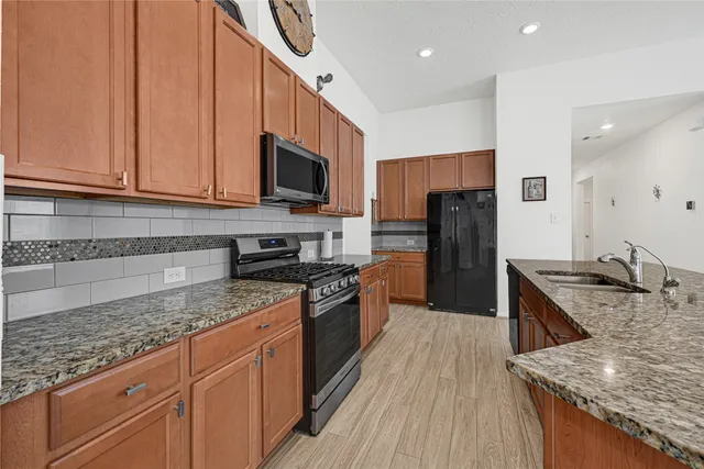 a large kitchen with granite countertop stainless steel appliances and wooden cabinets