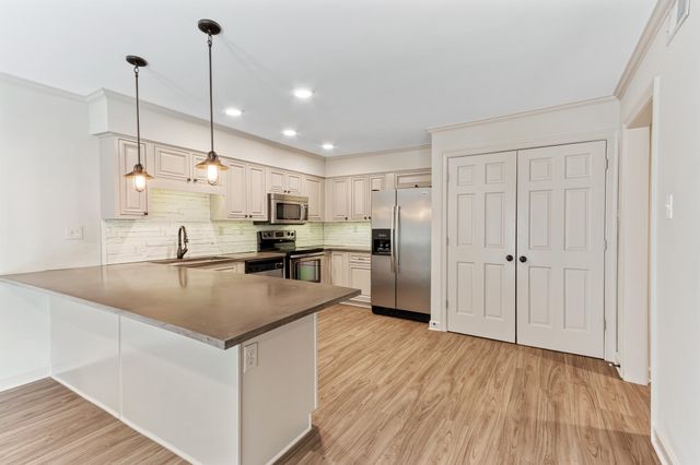 a kitchen with stainless steel appliances granite countertop a sink a refrigerator and a wooden floor
