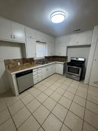 an empty room with chandelier fan and windows