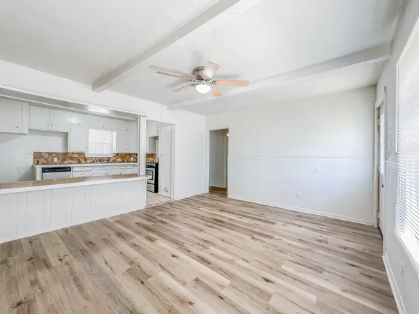 an empty room with wooden floor ceiling fan and windows