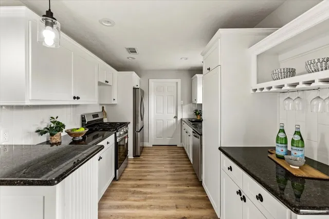 a kitchen with granite countertop a sink stove and refrigerator