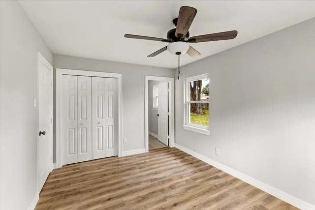 a view of empty room with wooden floor and fan
