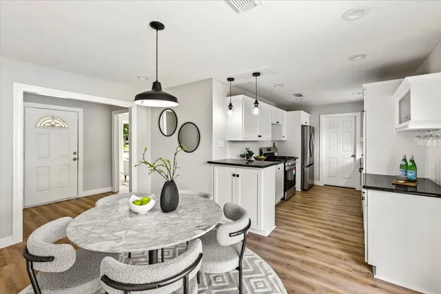 a kitchen with dining table stainless steel appliances and wooden floor