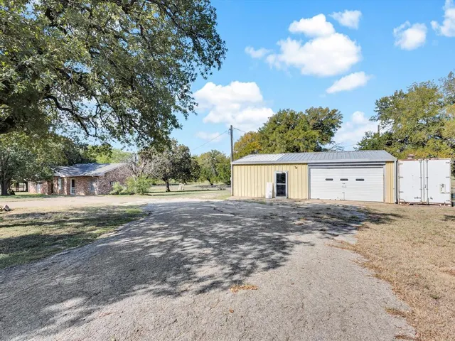 a view of a house with a yard and large trees