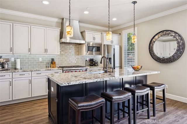 a kitchen with granite countertop a sink a stove top oven a clock and cabinets