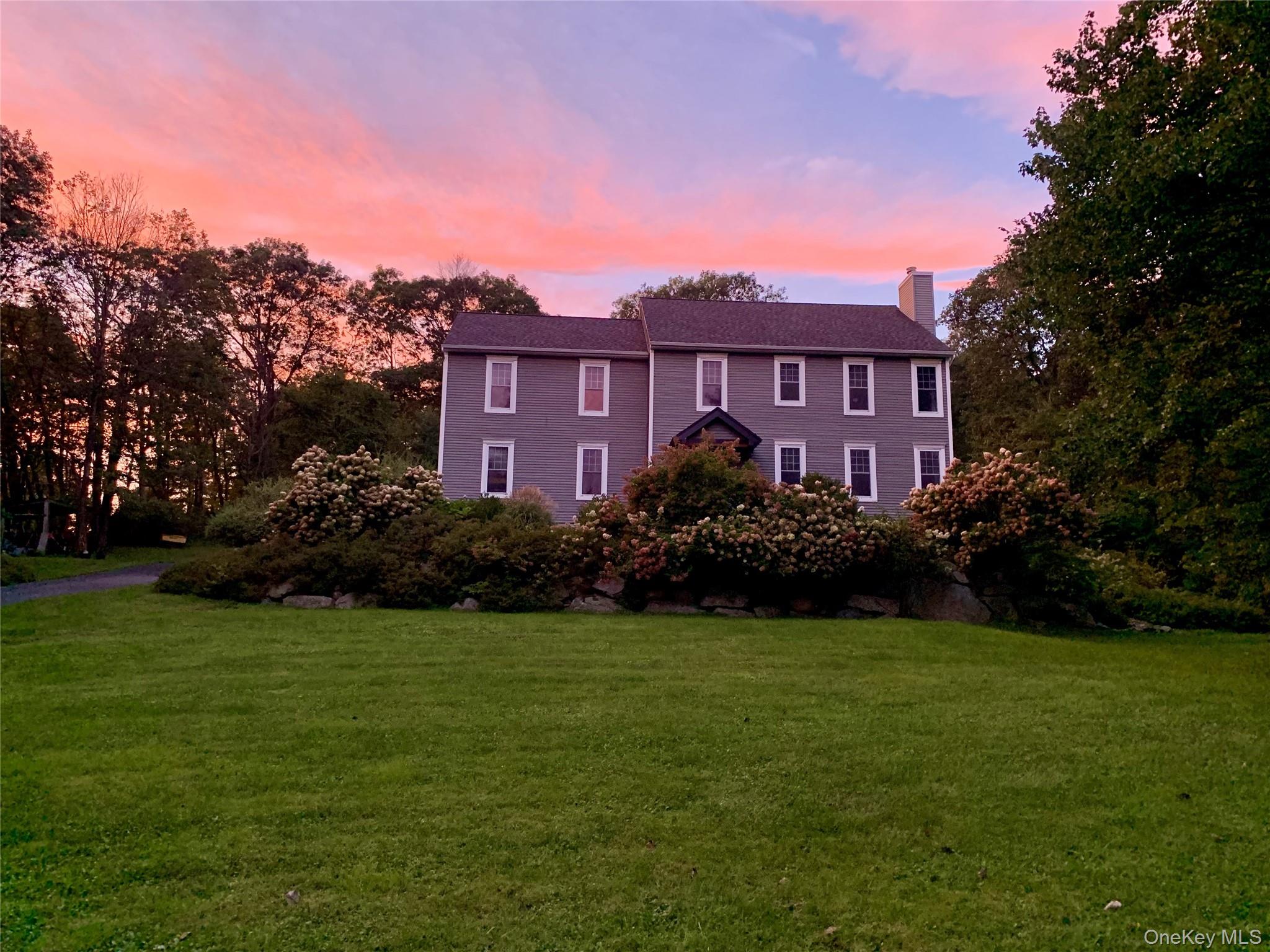 a view of a big house with a big yard and large trees