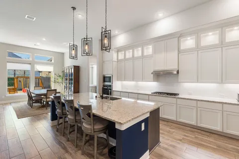 a kitchen with stainless steel appliances granite countertop a stove a refrigerator a sink and white cabinets